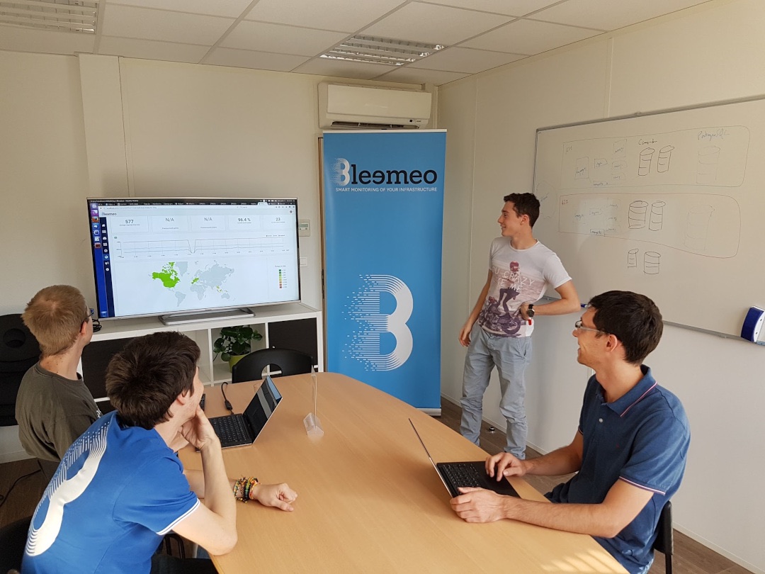 El equipo de Bleemeo en una sesión de trabajo alrededor de un panel de monitoreo en vivo